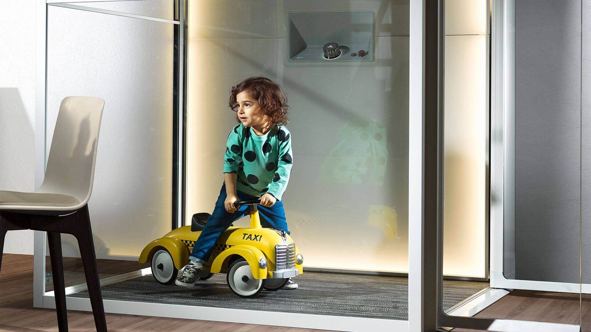 child is riding a toy car in a room