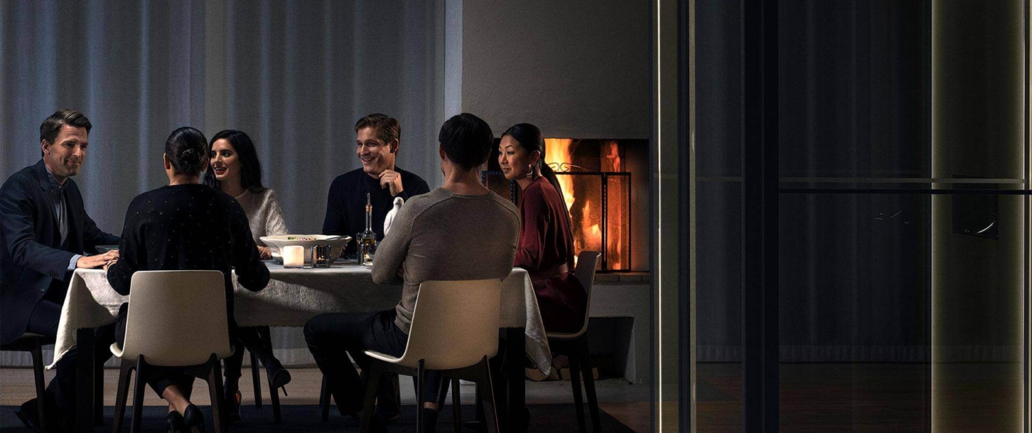 group of people sitting around a table in front of a fireplace